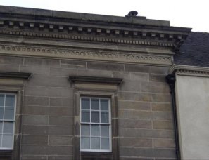 Roof hidden behind decorative stone eaves cornice